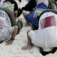 Các nhà hoạt động vì môi trường ở Cancun mặc áo có dán hình quốc kỳ các nước, đâm đầu vào cát để biểu thị việc các nước nhắm mắt làm ngơ trước hậu quả của biến đổi khí hậu - Ảnh: Reuters