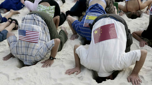 Environmental activists in Cancun, wearing their national flags, have stuck their heads in the sand to signify that countries are turning a blind eye to the effects of climate change.
